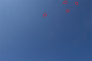 A blue sky showing four red circles that demonstrate where dust shows.